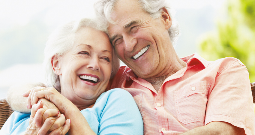 Happy couple cuddles and smiles to show their dental implants