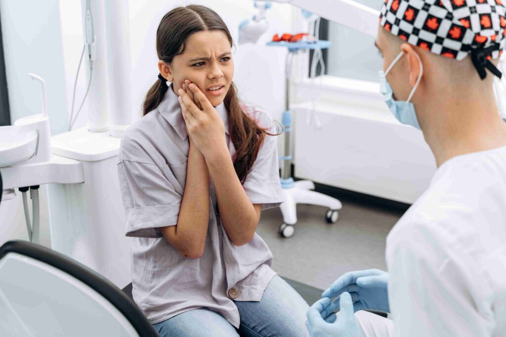 Young patient consulting a dentist about tooth pain in a dental office.