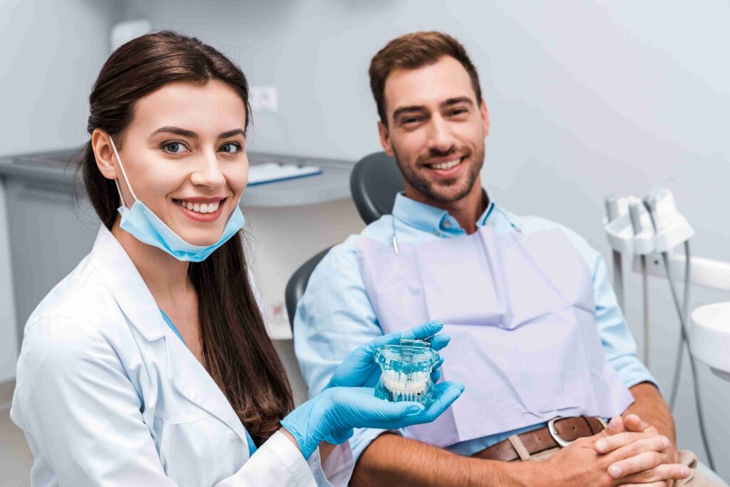 Dentist showing a dental model while consulting with a smiling patient.