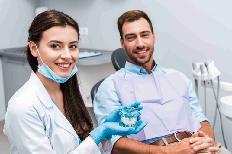 Dentist showing a dental model while consulting with a smiling patient.