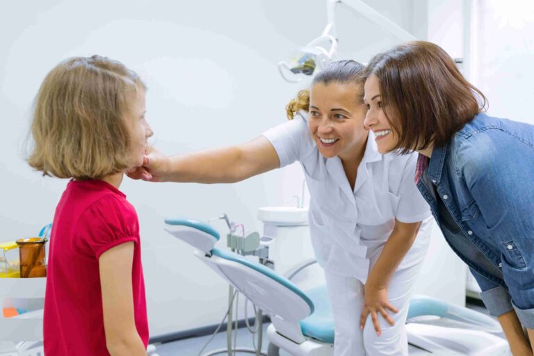 Dentist and parent helping a child feel comfortable during a dental visit.