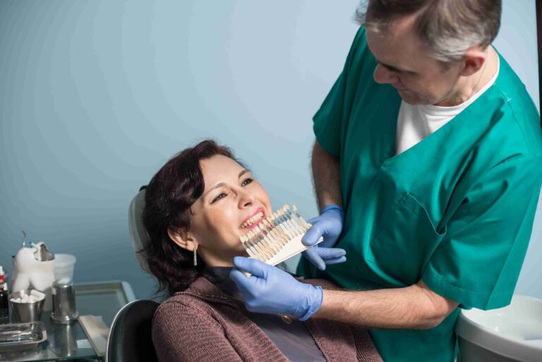 Dentist matching tooth shade for a smile makeover.